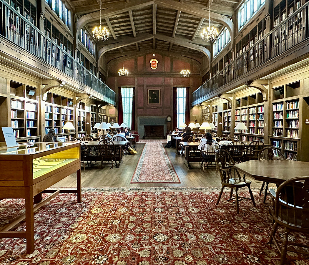 A silent study space with long and short tables as well as soft seating near the fireplace. Photo of historical library seating
